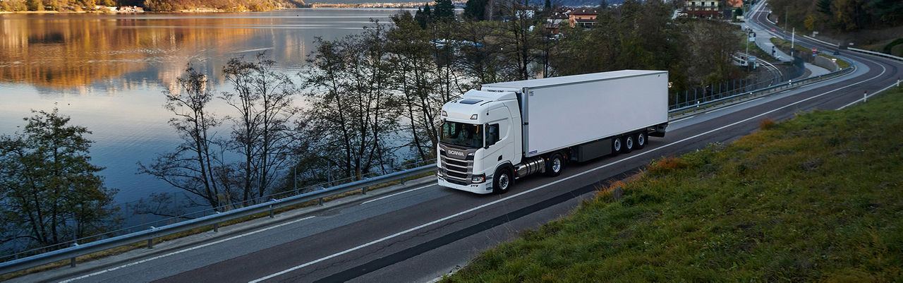 Bílé nákladní vozidlo Scania řady R při co nejhospodárnější jízdě po úzké silnici