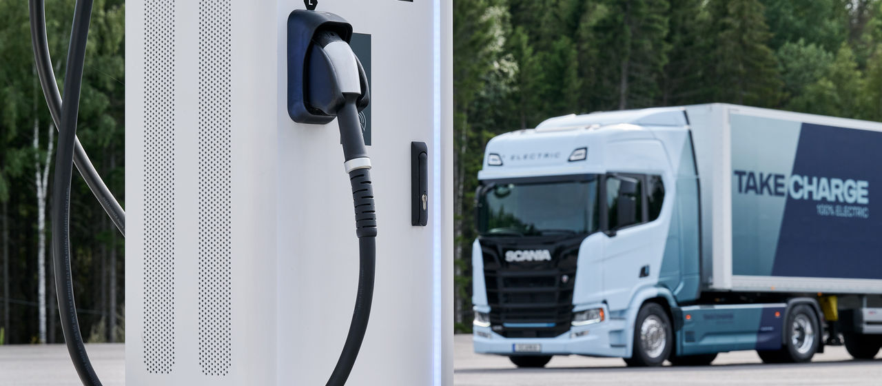 Scania ellastbil bakom laddstation
