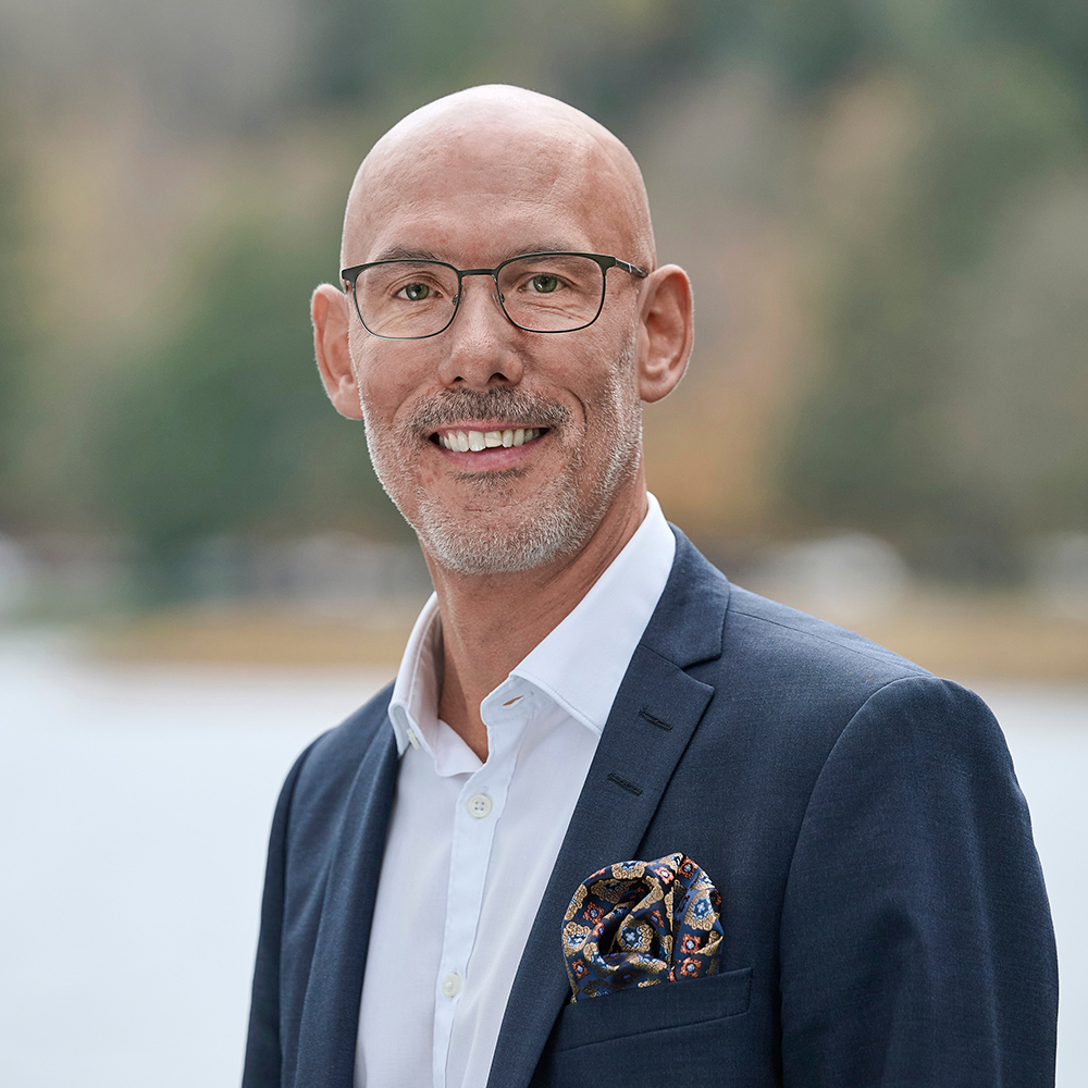 A portrait of Kristoffer Nyberg, Head of e-Truck Solution Management at Scania, standing infront of a lake.