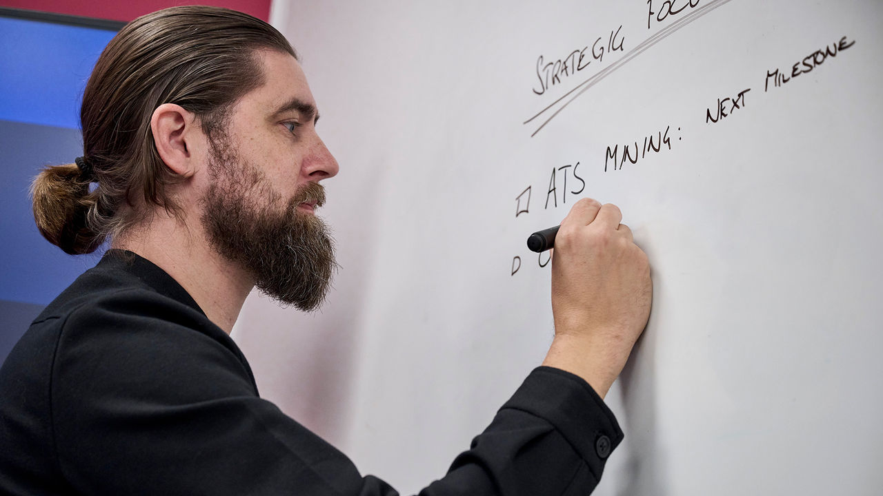 Daniel Frylmark, a Solutions Manager at TRATON Group R&D in action, writing strategies on a whiteboard.